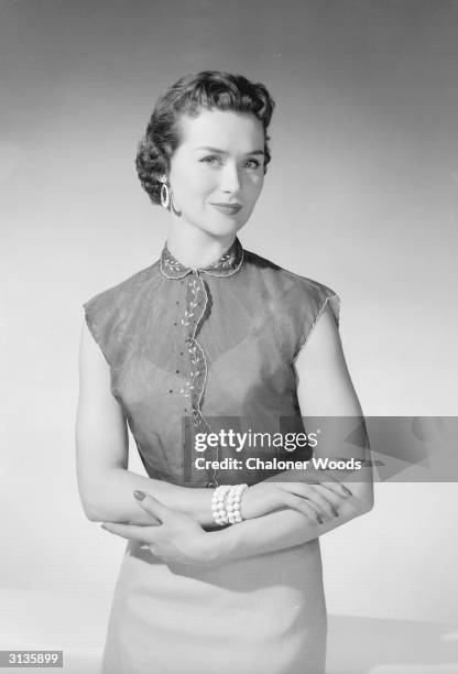 Woman modelling a short-sleeved filmy blouse with embroidery at the collar and seams.