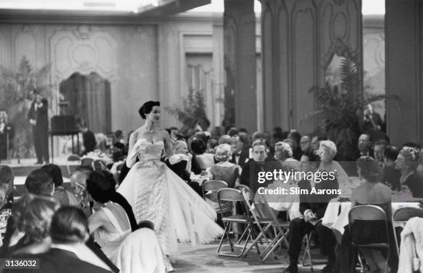 An evening dress being modelled at a fashion show held by Saks of Fifth Avenue, New York. The audience, who are in evening dress, are also being...