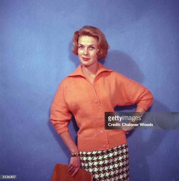 Woman modelling a peach coloured hip length cardigan designed by Bestway knitwear. It has three quarter length bat wing sleeves and an open collar.