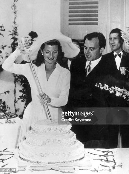 American actress Rita Hayworth with her husband, the Prince Aly Khan, cutting the cake on their wedding day.