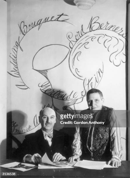 English composer Lord Berners with the American author Gertrude Stein in front of a poster for his ballet 'Wedding Bouquet' which was based on a play...