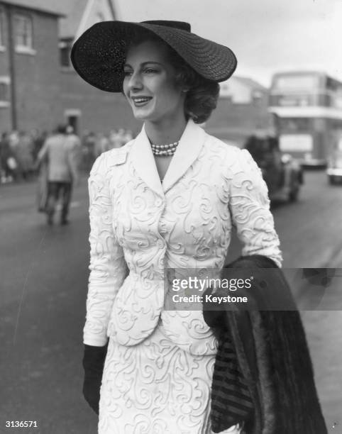 On the first day of the Royal Ascot meeting, model Fiona Campbell Walter wears a black straw hat, a white corded suit and pearl necklace and is...
