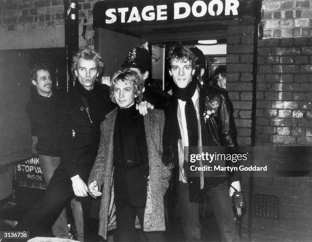 The pop group Police outside the stage door of a Hammersmith venue in west London, with a policeman standing behind them. From left to right, they...