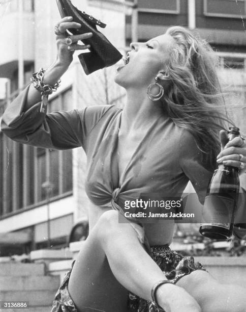 British fashion model Vicki Hodge drinking champagne from the George Best range of footwear from Stylo called Cagney, during a photocall at the...