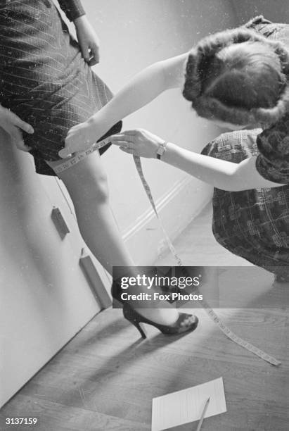 Tutor winds a tape measure around a girl's leg during a lesson at a glamour school which is designed to improve young ladies.