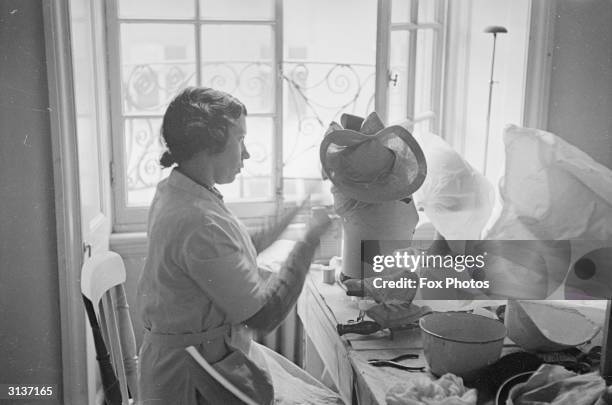 Milliner working for English fashion designer Norman Hartnell concentrating on a new hat.