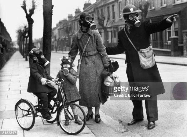 Warden gives directions to a mother and her two children during a World War II gas drill in Southend.