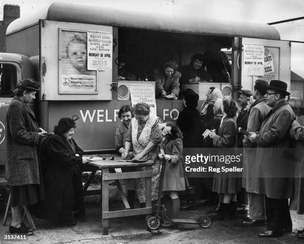 Miss I Maguire of the Tottenham Food Office distributes ration books to local housewives from a new mobile office, parked on White Hart Lane, London.