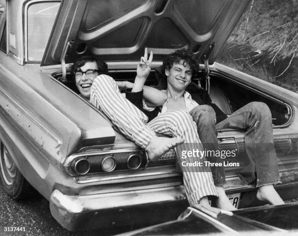 Two young men in the boot of a car after hitching a lift home from the Woodstock Music and Arts Fair.
