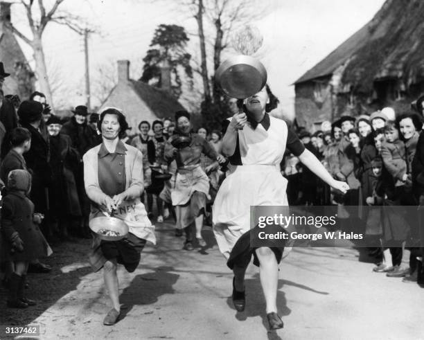 Housewives compete in the annual Shrove Tuesday Pancake Race at Olney, Buckinghamshire, for the prize of a prayer book and a kiss from the local...