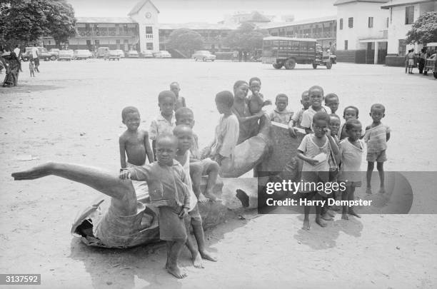 Children around a fallen statue of the self appointed president of Ghana, Kwame Nkrumah during the coup that overthrew his dictatorship.