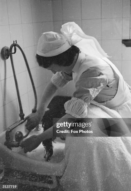 Nurse washing a patient's hair over the sink at Mayday Road Hospital in Croydon.