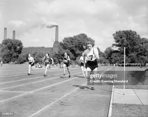 British athlete Heather Armitage running in Battersea Park, with the chimneys of the famous power station behind her.