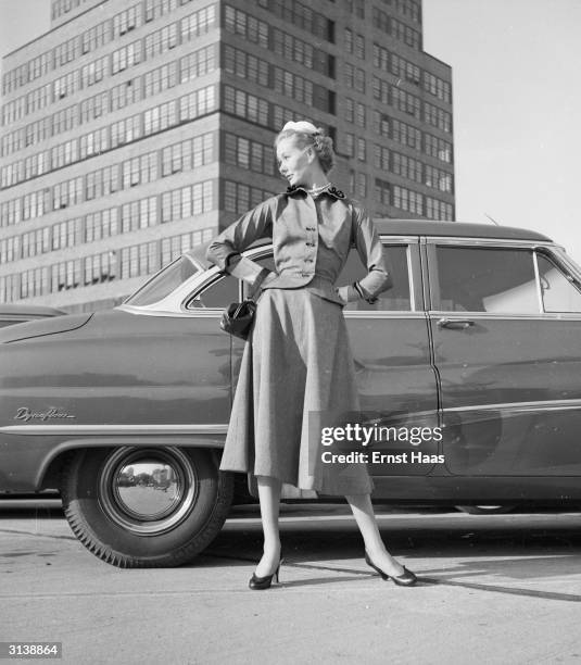 Vogue fashion model standing in front of a car in the shadow of the McGraw Hill building on West 42nd Street, New York.