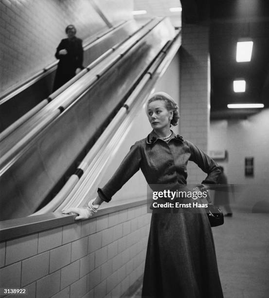 Premium Rates Apply 1952: A Vogue fashion model in the New York subway wearing a skirt and a high buttoned top with a fitted waist.