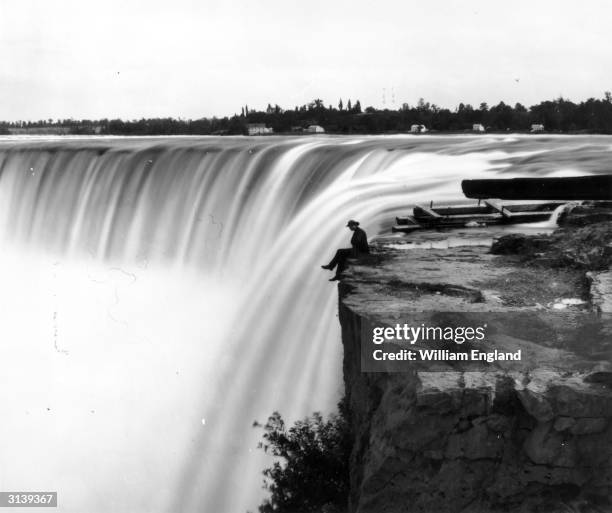 Man perches on Table Rock at the edge of the Horseshoe Falls, the crescent-shaped cataract on the Canadian side of Niagara Falls.