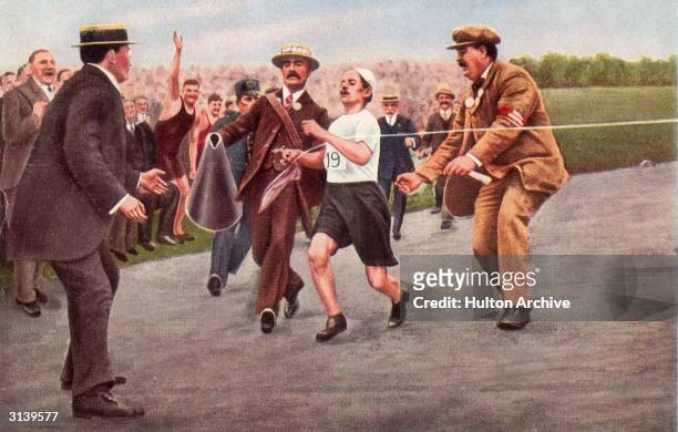 Dorando Pietri of Italy, on the verge of collapse, is helped across the finish line in the Marathon event of the 1908 Olympic Games in London. He was...