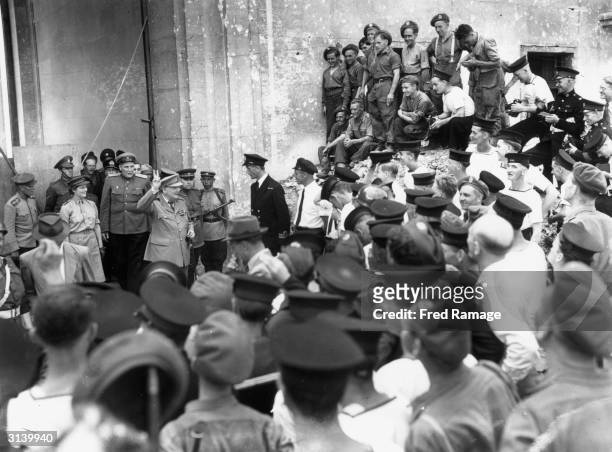 British politician and Prime Minister Winston Churchill giving the victory sign to men of the British Army and Navy, behind Churchill is his Russian...