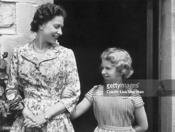 Queen Elizabeth II with her only daughter and second child, Princess Anne arm-in-arm in the gardens of Windsor Castle.