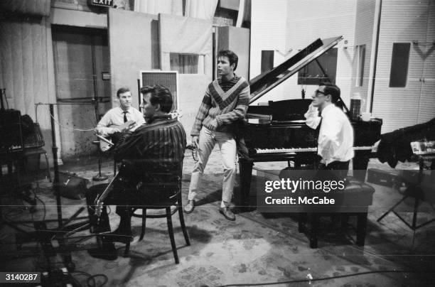 English singer Cliff Richard with members of his backing band, The Shadows, Hank B Marvin and Bruce Welch, at the EMI recording studios.