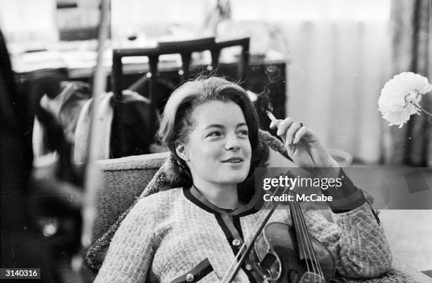 Austrian actress, Romy Schneider , taking a break from a violin lesson.
