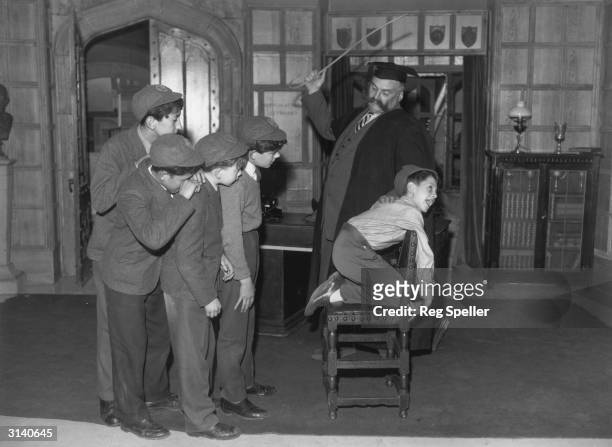 'Professor' Jimmy Edwards in rehearsal at Shepherds Bush TV studios is administering a flogging to one of the pupils of 'Chiselbury' school, Paul...