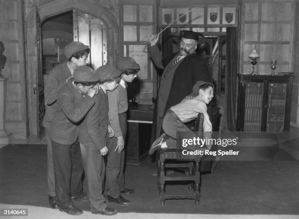 'Professor' Jimmy Edwards in rehearsal at Shepherds Bush TV studios is administering a flogging to one of the pupils of 'Chiselbury' school, Paul...