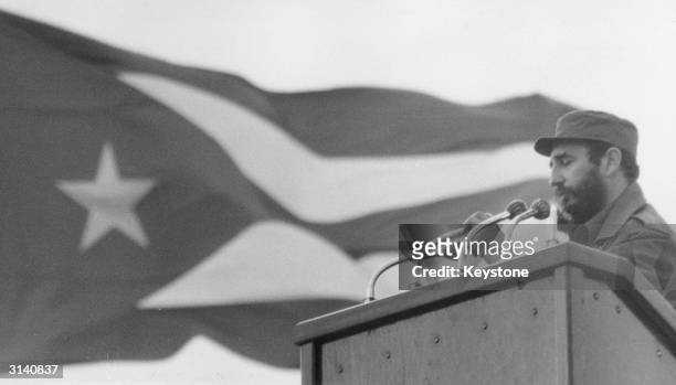Fidel Castro giving a speech with the national flag of Cuba in the background.