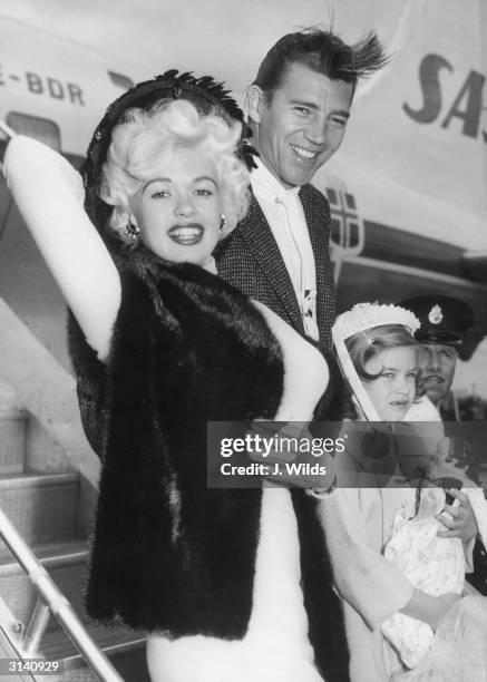 Hollywood sex symbol Jayne Mansfield arrives at London Airport with her husband Mickey Hargitay and her daughter Jayne Marie. She is to co-star with...