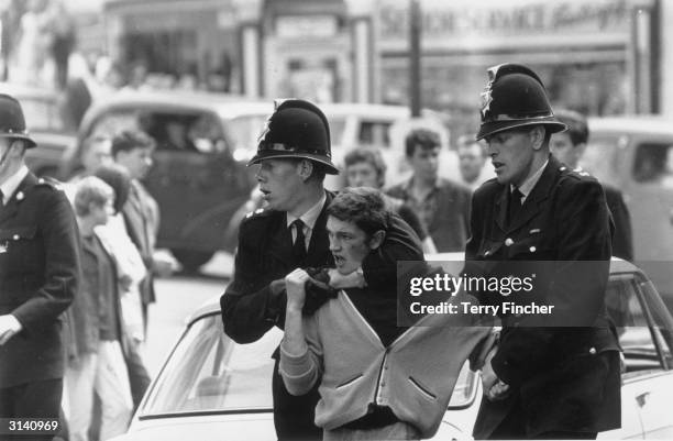 Policemen 'removing' a troublemaker during a clash between 'Mods' and 'Rockers' in Margate, Kent.