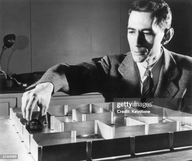 Dr Claude E Shannon a mathematician at the Bell Telephone Laboratories with an electronic mouse which has a 'super' memory and can learn its way...