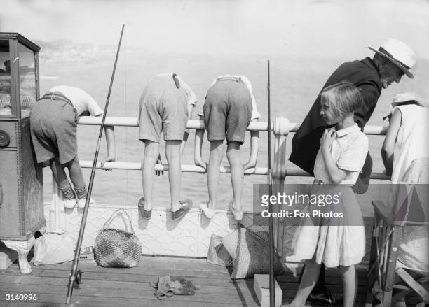 Row of boys lean far over the railings during a children's angling contest at Worthing, West Sussex.