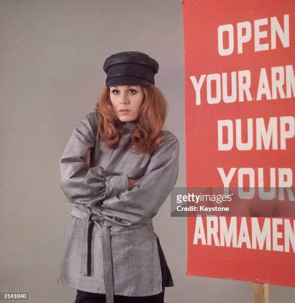 British model and actress Joanna Lumley, star of the TV series 'The New Avengers', dressed in a Russian-style tunic and cap, and standing next to a...