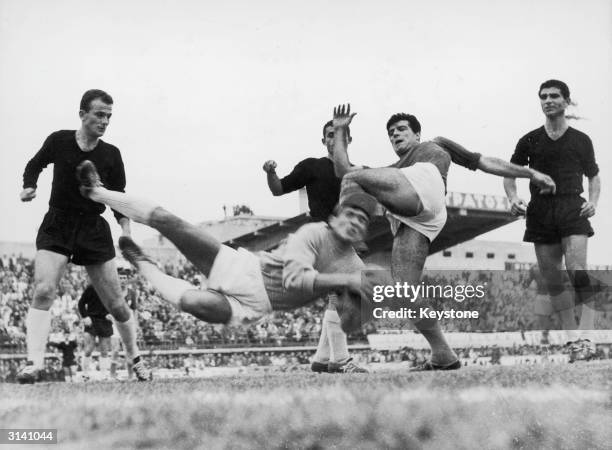 The goalkeeper of the Greek football team Nikaia catching the ball but receiving a painful kick in the back from a player from the opposing team,...