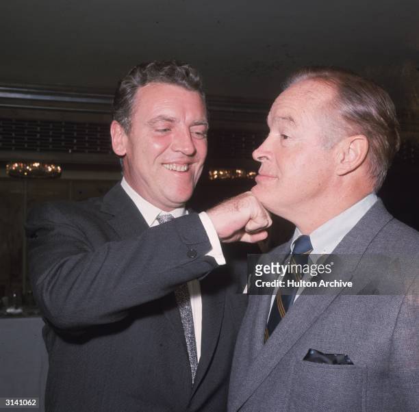 British-born American comedian and actor Bob Hope gets a friendly punch to the jaw from Irish radio and television personality Eamon Andrews.