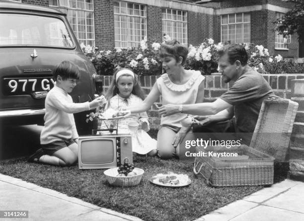Family having a picnic beside a Philips T-Vette which operates on a 12 volt battery and is the first truly portable transistor battery with an 11...