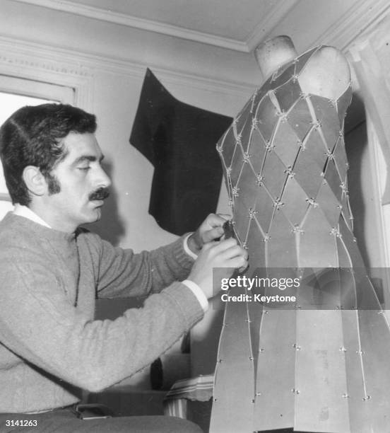 Spanish born dress designer Paco Rabanne at work on one of his metallic dresses.