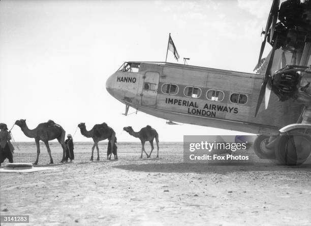 Line of camels is led past the Imperial Airways Handley Page H.P.42 airliner, 'Hanno', at Gwadar - then an overseas possession of Oman on the shore...