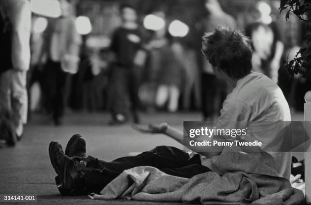 homeless man begging on street at night (b&w) - aumône photos et images de collection