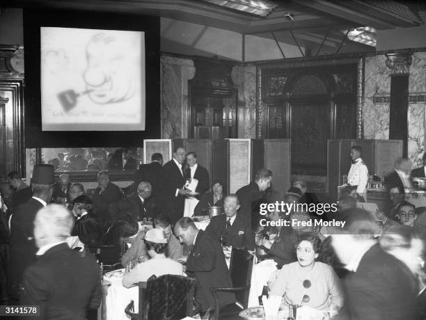 Diners at the Trocadero restaurant in London hear the results of the General Election. The screen cartoon caption reads 'Listen to one who nose'...