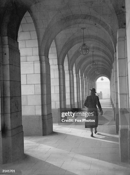 Woman walks down a covered archway at Shell Mex House, London.