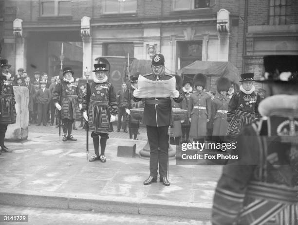 Flanked by several Yeomen of the Guard, a policeman reads the funeral proclamation of King George V, just before the new King Edward VIII leaves for...