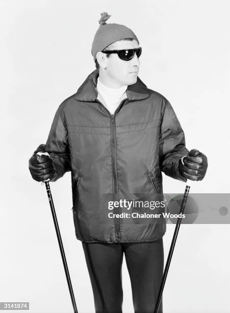 Nylon ski-jacket with zip front and slant pockets worn with a knitted 'beanie' hat and sunglasses.