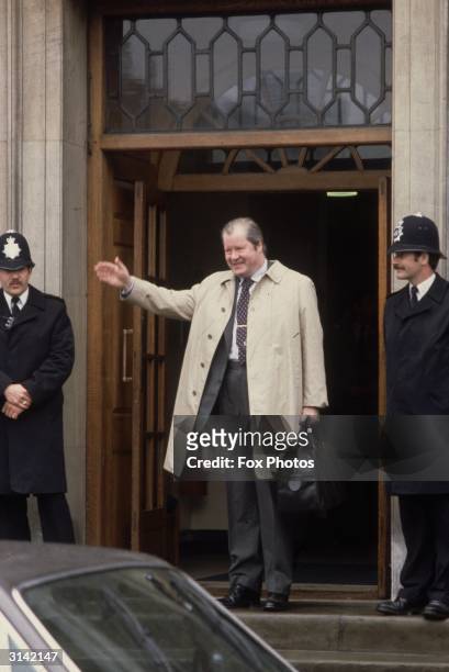 The 8th Earl Spencer , father of Diana, Princess of Wales, leaves a building guarded by two policemen.