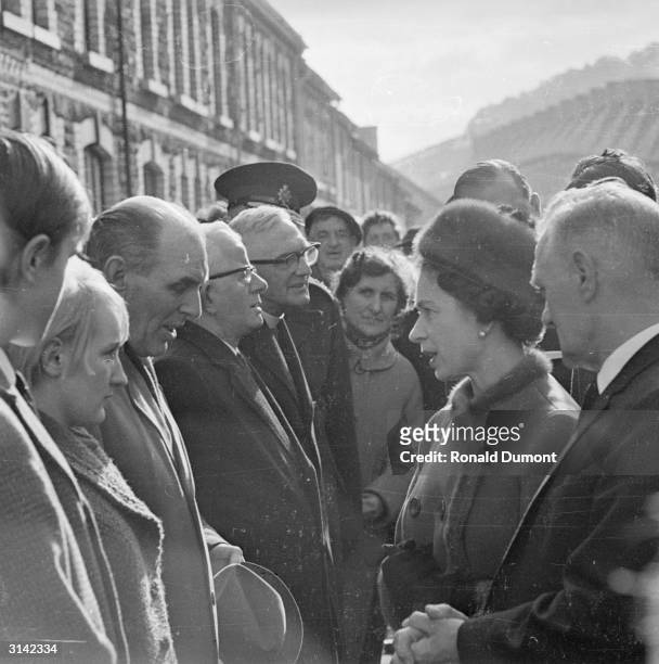 Queen Elizabeth II visits Aberfan in Wales a few days after a coal tip collapsed on the local school, killing 141 children and four adults.