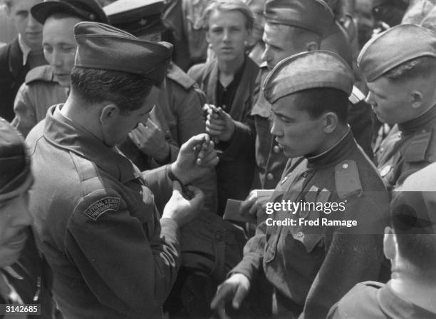 An official US war photographer tries on a watch at the daily 'Persian Bazaar' outside the Reichstag in post-war Berlin. Allied troops and Germans...