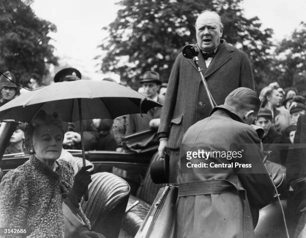 Winston Churchill giving a speech from the back of a car during his electioneering campaignat the end of WW II. With him in the car is his wife...