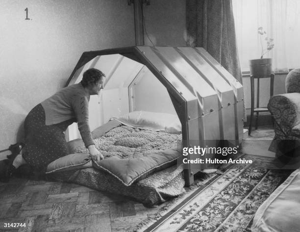 Woman makes the bed in an indoor bomb shelter.
