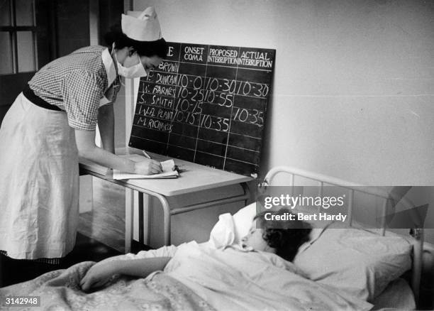 Nurse at the Netherne Mental Hospital near Coulsdon, Surrey, logs the times that a patient's coma is induced by insulin and interrupted by a dose of...