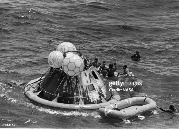 Navy rescue crew member with the Apollo 12 astronauts Charles 'Pete' Conrad Jr, Richard F Gordon Jr and Alan L Bean in a life raft during recovery...